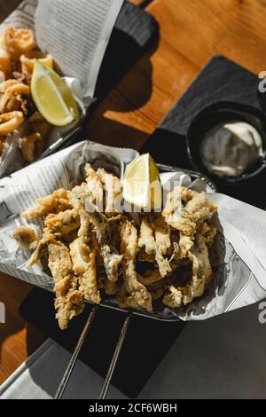 Dall'alto di gamberi in pastella con fetta di limone sul piatto servito con salsa al ristorante Foto Stock