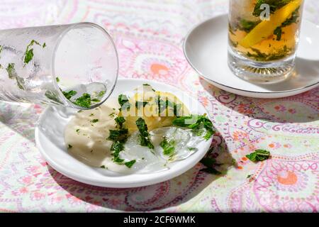 Tè freddo con cubetti d'acqua surgelati versati sul piattino con limone e menta Foto Stock