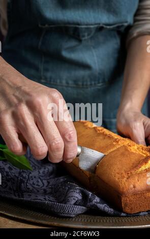 Mani da donna non riconoscibili tagliate a metà con un coltello una torta di limone fatta in casa Foto Stock