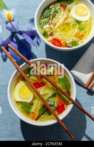 Da sopra ramen orientale sana zuppa di tagliatelle con shiitake, spinaci, carote, uova e peperoncini sul tavolo del ristorante Foto Stock