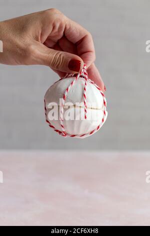 Persona non riconoscibile tagliata che tiene una casa bianca Zefir tradizionale russo dessert avvolto con corda su sfondo rosa Foto Stock