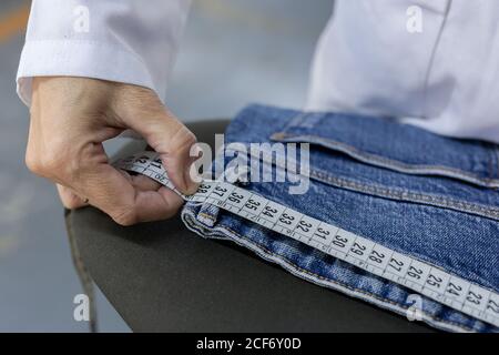 Donna operatrice in fabbrica tessile che controlla la qualità dei capi. Produzione industriale Foto Stock