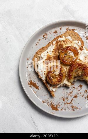 Pane tostato fatto in casa con formaggio spalmabile, banana fritta, miele e cannella.concetto alimentare vegetariano. Foto Stock