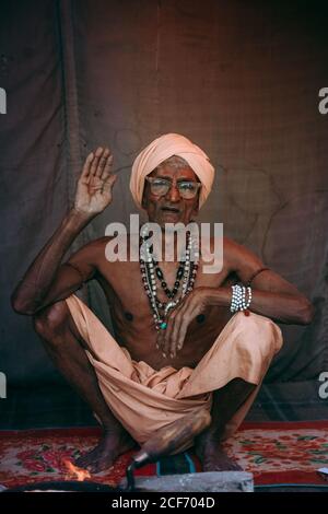 Allahabad, India - FEBBRAIO, 2018: Primo piano ritratto di un anziano indiano che indossa abiti tradizionali seduti sul pavimento Foto Stock