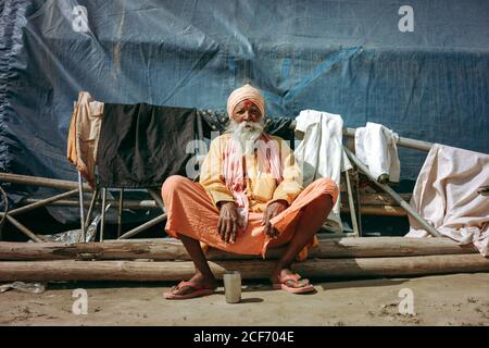 Allahabad, India - FEBBRAIO, 2018: Primo piano ritratto di un anziano indiano che indossa abiti tradizionali seduti sul pavimento Foto Stock