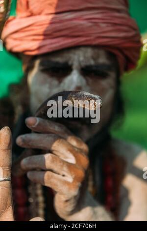 Varanasi, India - Febbraio, 2018: Uomo santo indiano sadhu con faccia dipinta e turbante sulla testa che tiene il serpente nelle mani Foto Stock