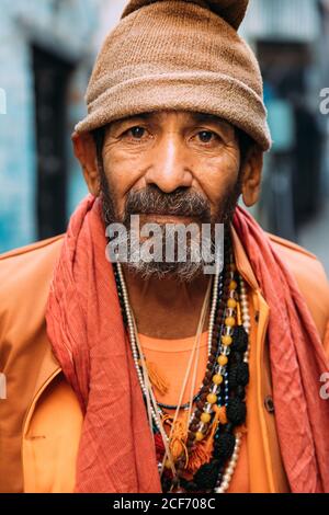Varanasi, India - FEBBRAIO, 2018: Primo piano ritratto di un anziano indiano che indossa abiti tradizionali arancioni contro sfondo sfocato Foto Stock