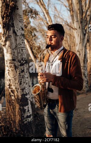 giovane musicista che suona il sassofono al tramonto Foto Stock