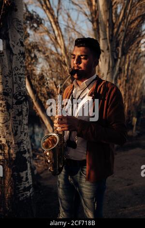 giovane musicista che suona il sassofono al tramonto Foto Stock