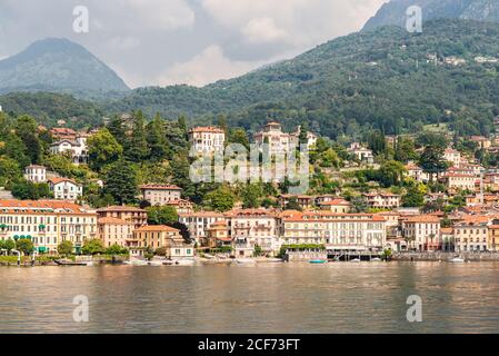 Panorama della città di Menaggio sul Lago di Como in Italia. Architettura luminosa con edifici colorati. Città Embankment con i turisti. Vista dall'acqua. Foto Stock