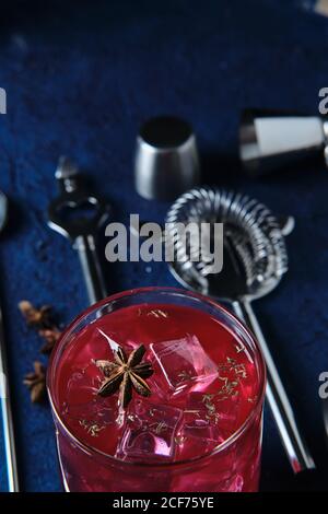 Deliziosi cocktail rossi e utensili da barman sul tavolo Foto Stock