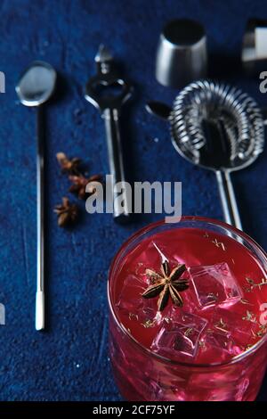 Deliziosi cocktail rossi e utensili da barman sul tavolo Foto Stock