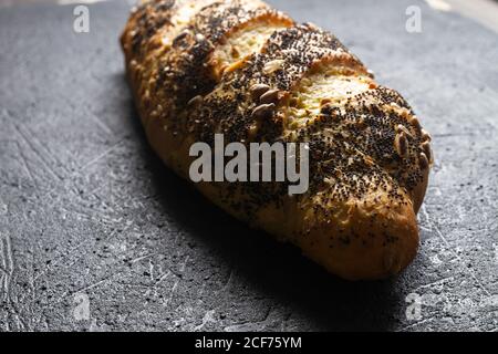 Pagnotta di pane fresco e croccante con grani e. semi di papavero su una superficie grigia con texture Foto Stock