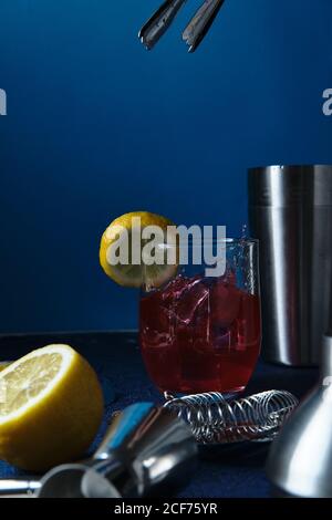 Deliziosi cocktail rossi e utensili da barman sul tavolo Foto Stock