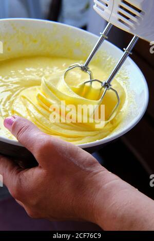 Da sopra anonima Donna uso mixer per preparare pastella per pasticceria in cucina a casa Foto Stock