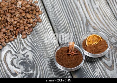 Chicchi di caffè. Caffè macinato in contenitori e spezie. Su una superficie di tavole di pino spazzolato dipinte in bianco e nero. Foto Stock