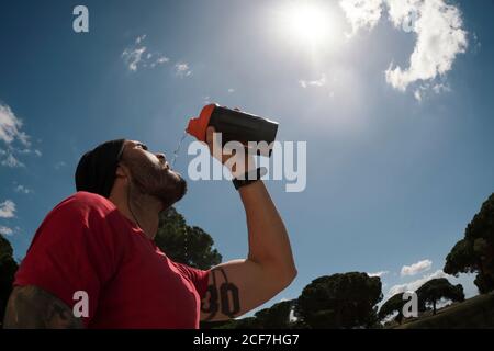 uomo che beve durante l'allenamento Foto Stock