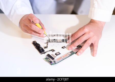 Giovane uomo che ripara il dispositivo moderno Foto Stock