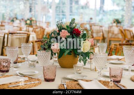 Bouquet di fiori unico e semplice in vaso su un tavolo festoso decorato con vetreria nel ristorante Foto Stock