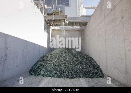 Dettagli con frammenti di vetro che cadono da un nastro trasportatore su una pila in un impianto di riciclaggio del vetro. Foto Stock