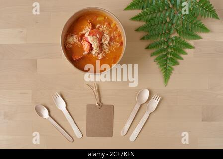 Vista dall'alto su gustoso riso e aragosta con sugo servito in contenitore di cartone e posto su tavolo di legno con monouso utensili Foto Stock