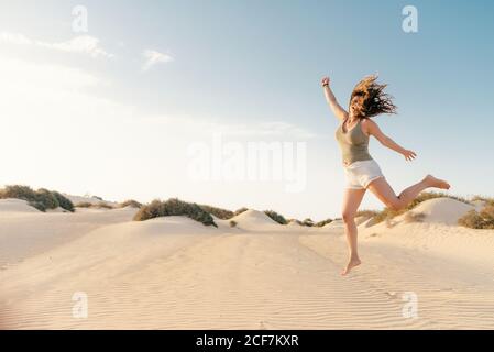 Donna attiva che corre nel deserto asciutto a piedi nudi Foto Stock