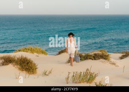 Donna attiva in pantaloncini bianchi a piedi spiaggia sabbiosa Foto Stock