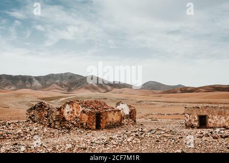 Vecchi edifici dilapidati nel deserto di montagna sotto il cielo nuvoloso Foto Stock