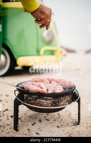 Uomo in scatola cucina su campeggio stufa accanto al mini van parcheggiato Foto Stock