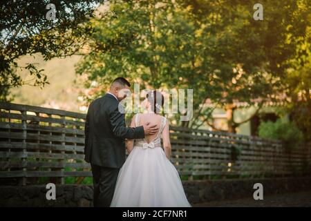 Sposo sorridente e sposa abbracciano e baciano nel parco Foto Stock