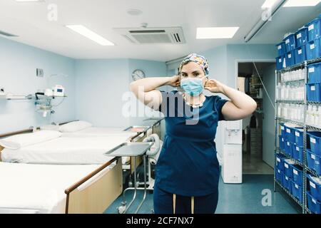 Medico in uniforme blu ospedale in piedi e pronti per chirurgia nel corridoio della clinica guardando la macchina fotografica Foto Stock