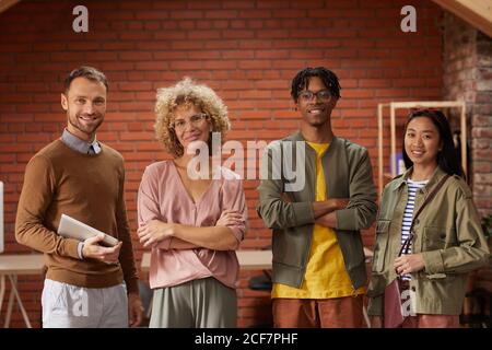 Ritratto di un team di business creativo multietnico in piedi con le braccia incrociati e sorridenti alla fotocamera in ufficio Foto Stock