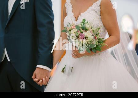 groom di raccolto irriconoscibile in smoking elegante e sposa in elegante abito da sposa in piedi insieme durante la cerimonia Foto Stock