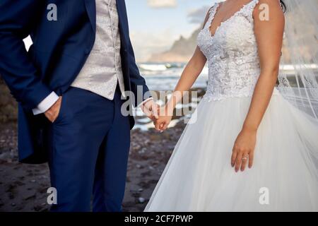 groom di raccolto irriconoscibile in smoking elegante e sposa in elegante abito da sposa in piedi insieme durante la cerimonia Foto Stock