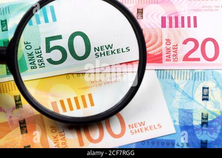 Nuovi shekels israeliani in una lente d'ingrandimento uno sfondo di affari Foto Stock