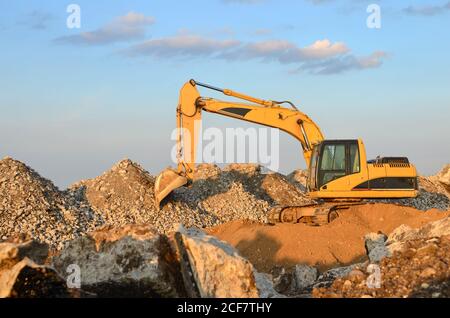 Escavatore in cantiere o cava mineraria per la frantumazione di calcestruzzo vecchio in ghiaia e successiva produzione di cemento. Retroescavatore in discarica con conr Foto Stock