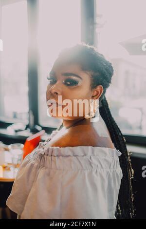 Ritratto con vista laterale di una bella giovane donna nera ricurva e luminosa con vestito a spalla in piedi Foto Stock