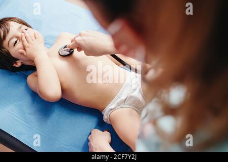 Medico con stetoscopio che esamina il bambino in clinica Foto Stock