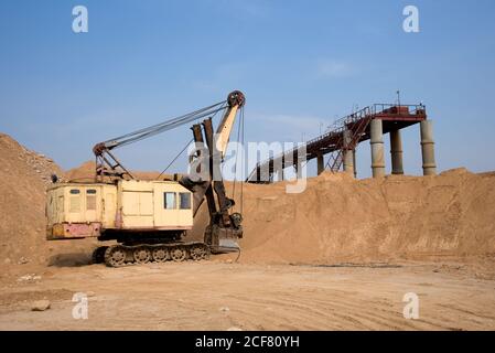 Enorme escavatore minerario nel pozzo di sabbia aperto. Più grande scavatore che lavora in cava. Macchina cingolata più grande con pala elettrica. Polvere elettrica per impieghi pesanti Foto Stock