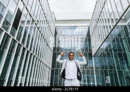L'uomo nero entusiasta gioisce alzando le mani in su Foto Stock