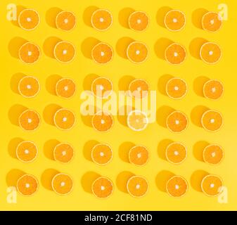 Set di bella carta da parati con arance a fette su sfondo giallo brillante. Foto Stock