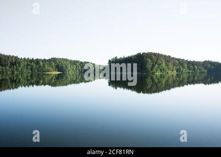 Vista panoramica del cielo blu e del grande lago trasparente circondato da foresta densa Foto Stock