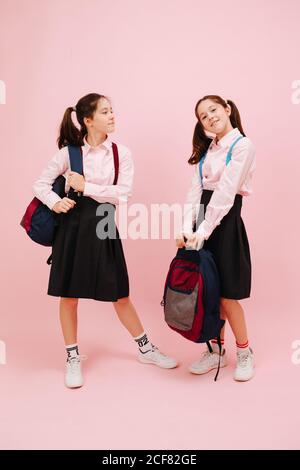 Carino felice bambine gemelle che posano con i loro zaini. Angolo basso Foto Stock