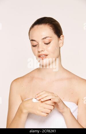 Donna felicissima che applica crema di recupero sulle mani Foto Stock