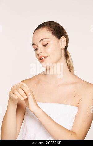 Donna felicissima che applica crema di recupero sulle mani Foto Stock