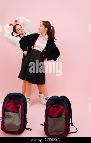 Ragazze gemelle giocose, inclinate da lati diversi, guardandosi l'un l'altro Foto Stock