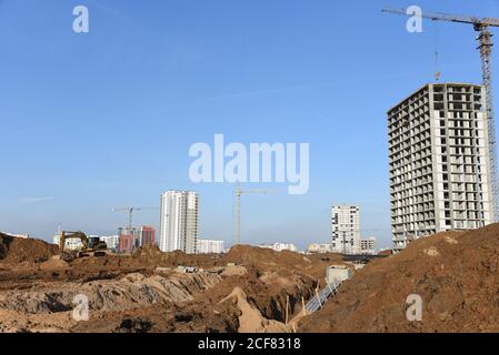 Posa di tubi fognari sotterranei nel cantiere. Installazione della rete idrica e fognaria sanitaria su gru a torre di fondo e di sk blu Foto Stock