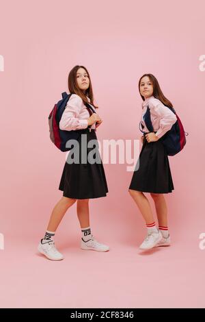 Felici le ragazze gemelle che posano con i loro zaini. Angolo basso Foto Stock