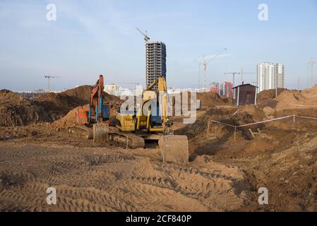 Gruppo di escavatori per scavare trincee in un cantiere per fondare e installare tubi per tempeste. Scavo del retroescavatore per fossato della tubazione. Foto Stock