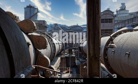Vista di stoccaggio contenitori invecchiati con gas localizzati sul territorio di area industriale di fronte a torri d'acqua e abbandonato costruzione Foto Stock